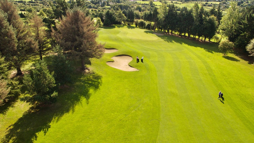 Aerial view of Edmondstown Golf Club surrounded by trees with some golfers and a sand bunker