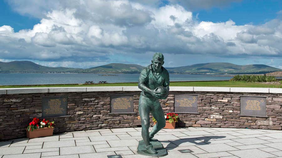 Bronze statue of Kerry footballer Mick O Dwyer with the background of the bay visible behind