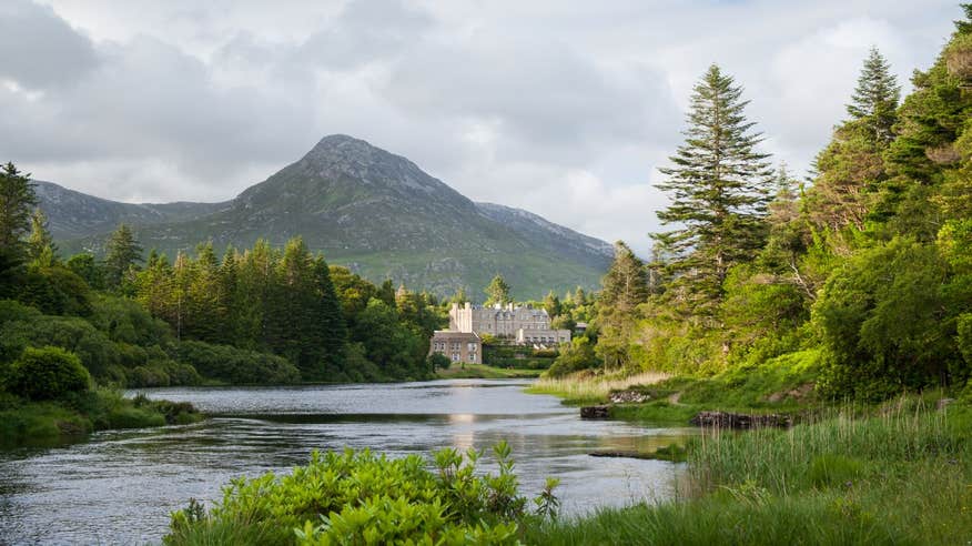 A castle reflected in a lake with a backdrop of mountains in Connemara, Galway