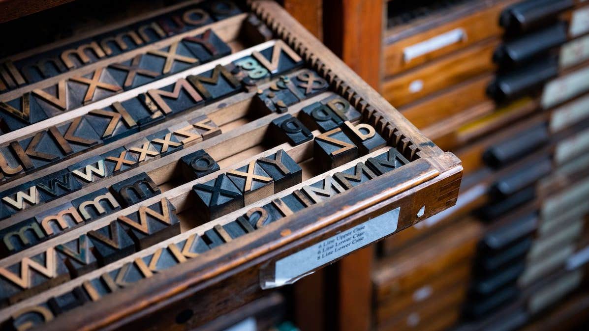 Image of a wooden tray of small print letters made from wood and metal.