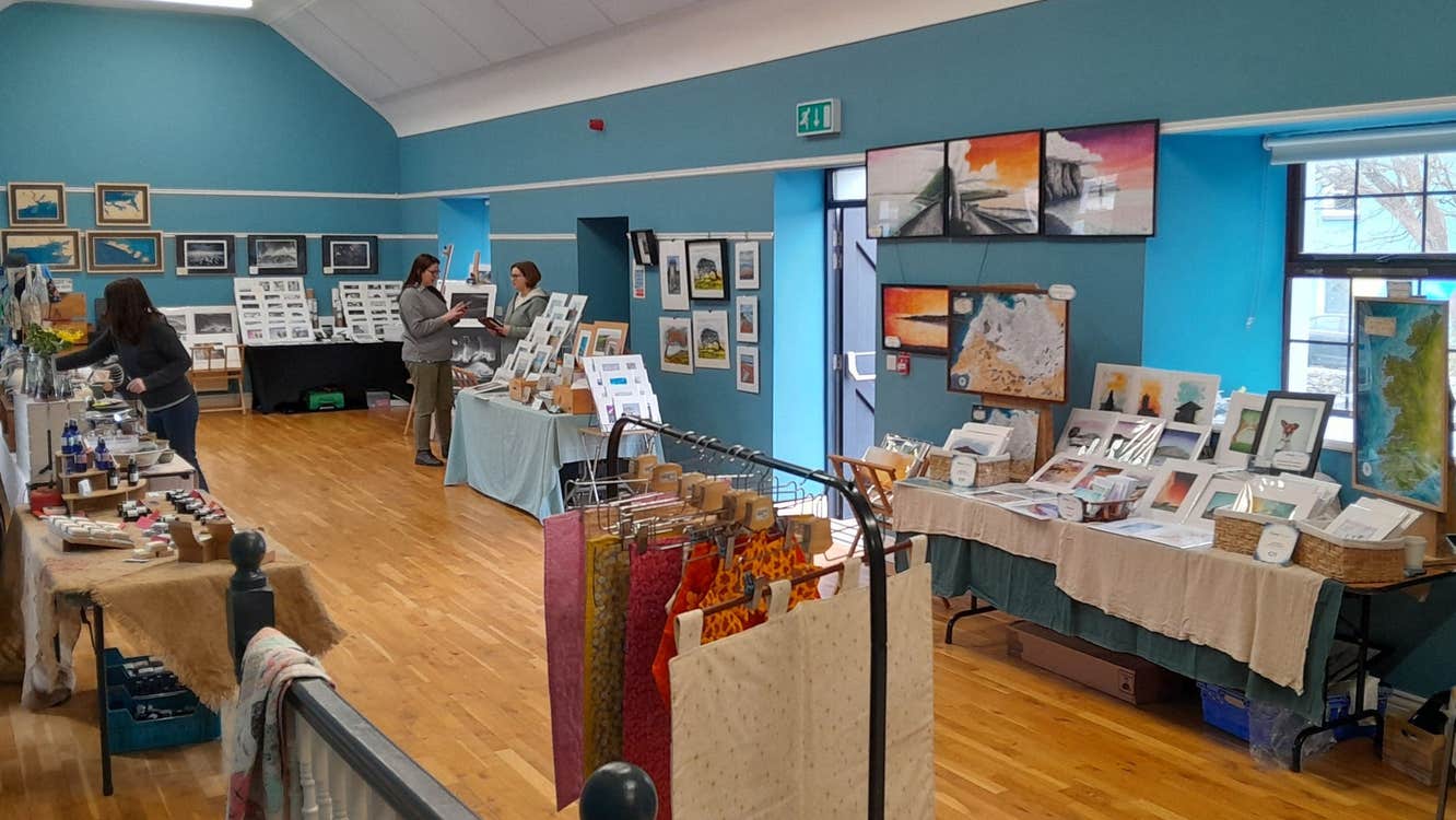 Room with blue walls and a wooden floor with tables displaying products all around