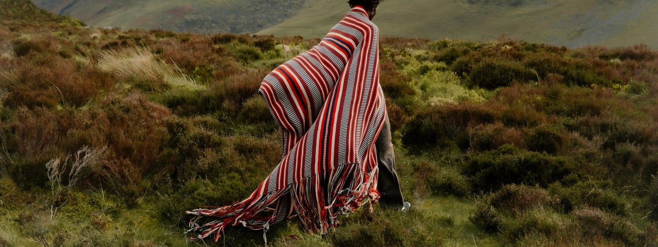 A person wearing a large wrap around and colourful shawl type of clothing in the outdoors