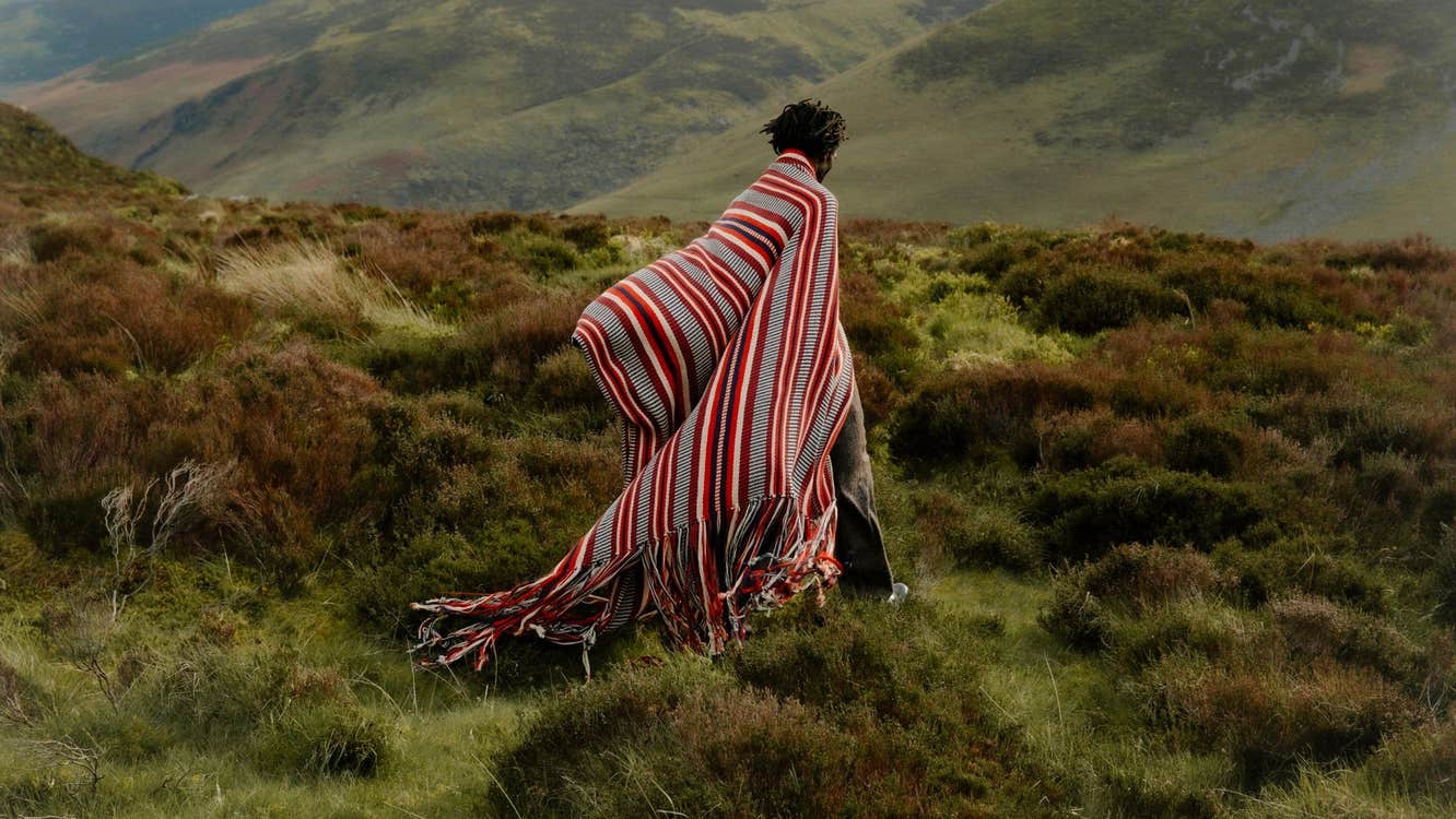 A person wearing a large wrap around and colourful shawl type of clothing in the outdoors