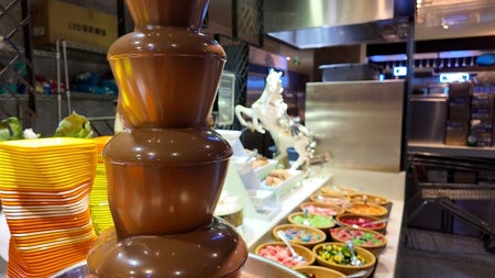 Chocolate fountain with various salads in bowls in the background