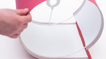 A participant smooths the fabric around a frame while assembling a handmade lampshade