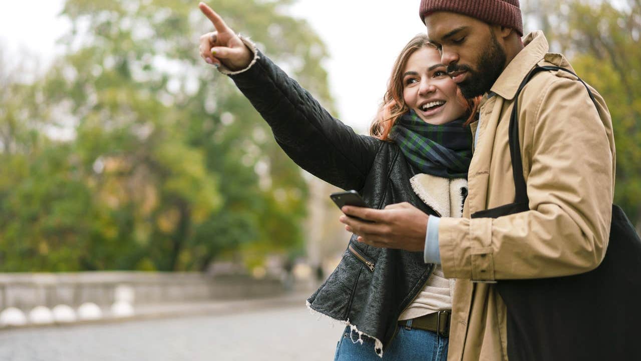 Lady pointing and gentleman looking at the Fun Explore interactive game on his mobile phone