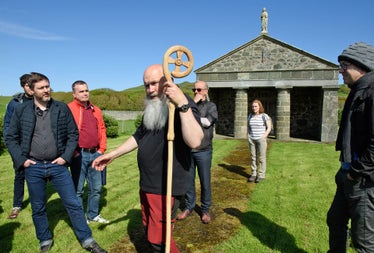 Lambay Nature Walking Tours group by a chapel with a guide holding a decorated staff