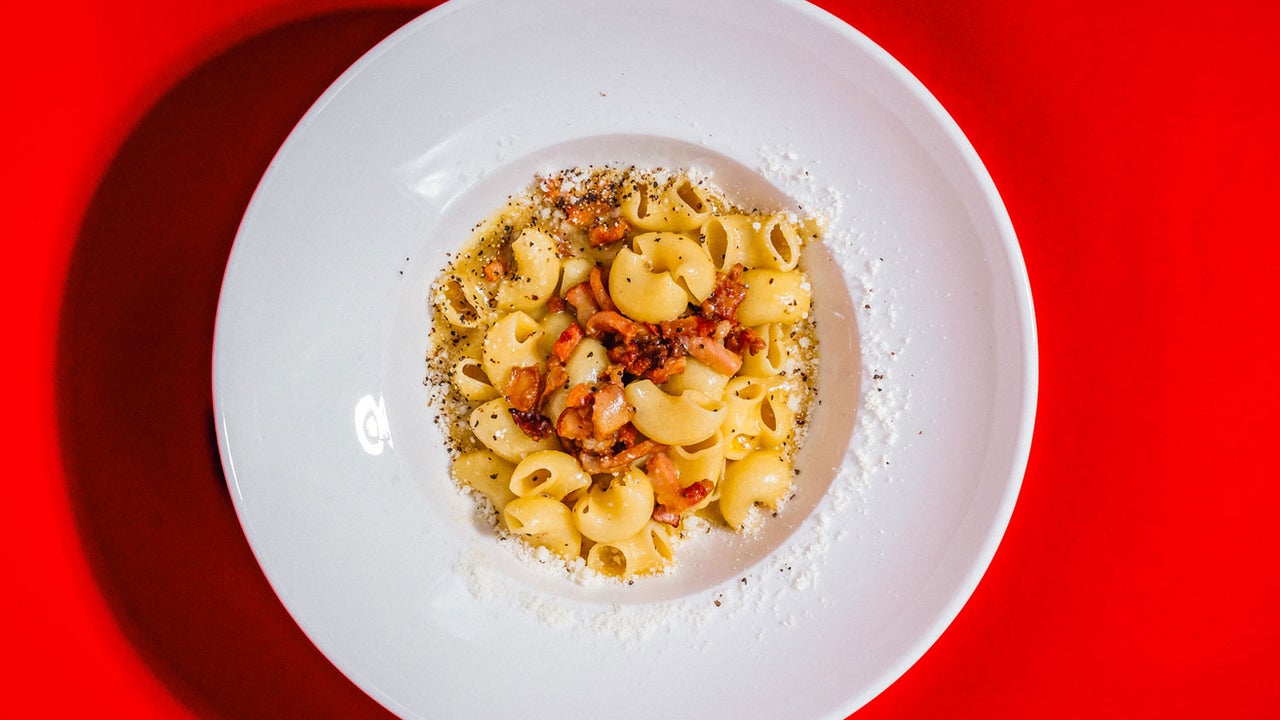 A dish of pasta on a white bowl on a red table cloth at TONI Italian restaurant