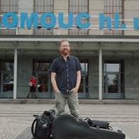 A master storyteller, Niall Connolly, a man standing in front of a building with guitar case and bags