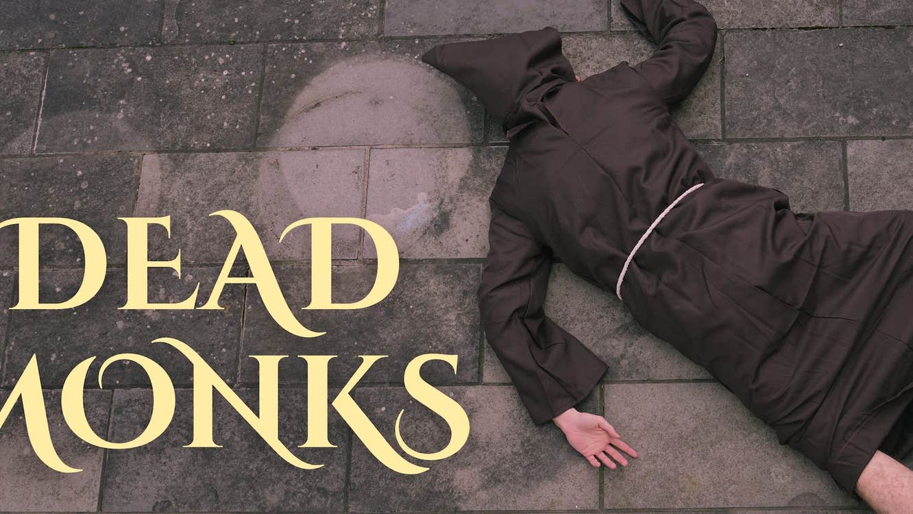 A person in brown monk's dress lying face down on stone floor