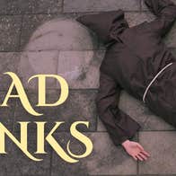 A person in brown monk's dress lying face down on stone floor