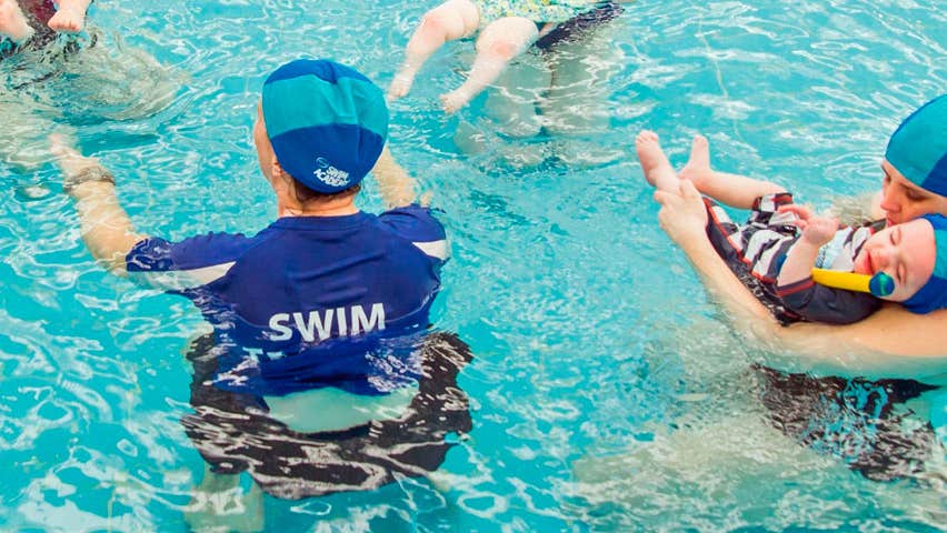 A swimming instructor with clients in the swimming pool