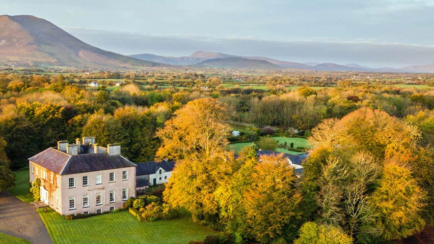Aerial view of Enniscoe House in woodlands and Mount Nephin in the background