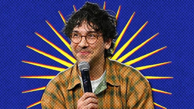 American comedian and writer, Rick Glassman - a smirking man holding a mic up to his chin.