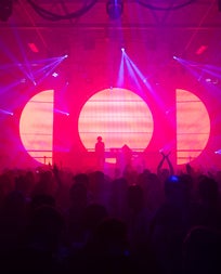 Brightly lit stage with a dj standing at his turntables