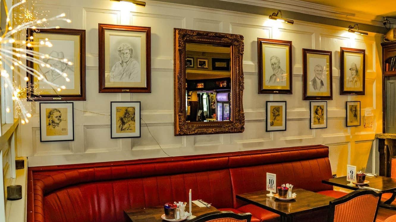 Red seat with tables set for services and pictures and a mirror on the wall above