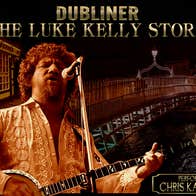 A man with curly hair is playing guitar and singing into a mic.