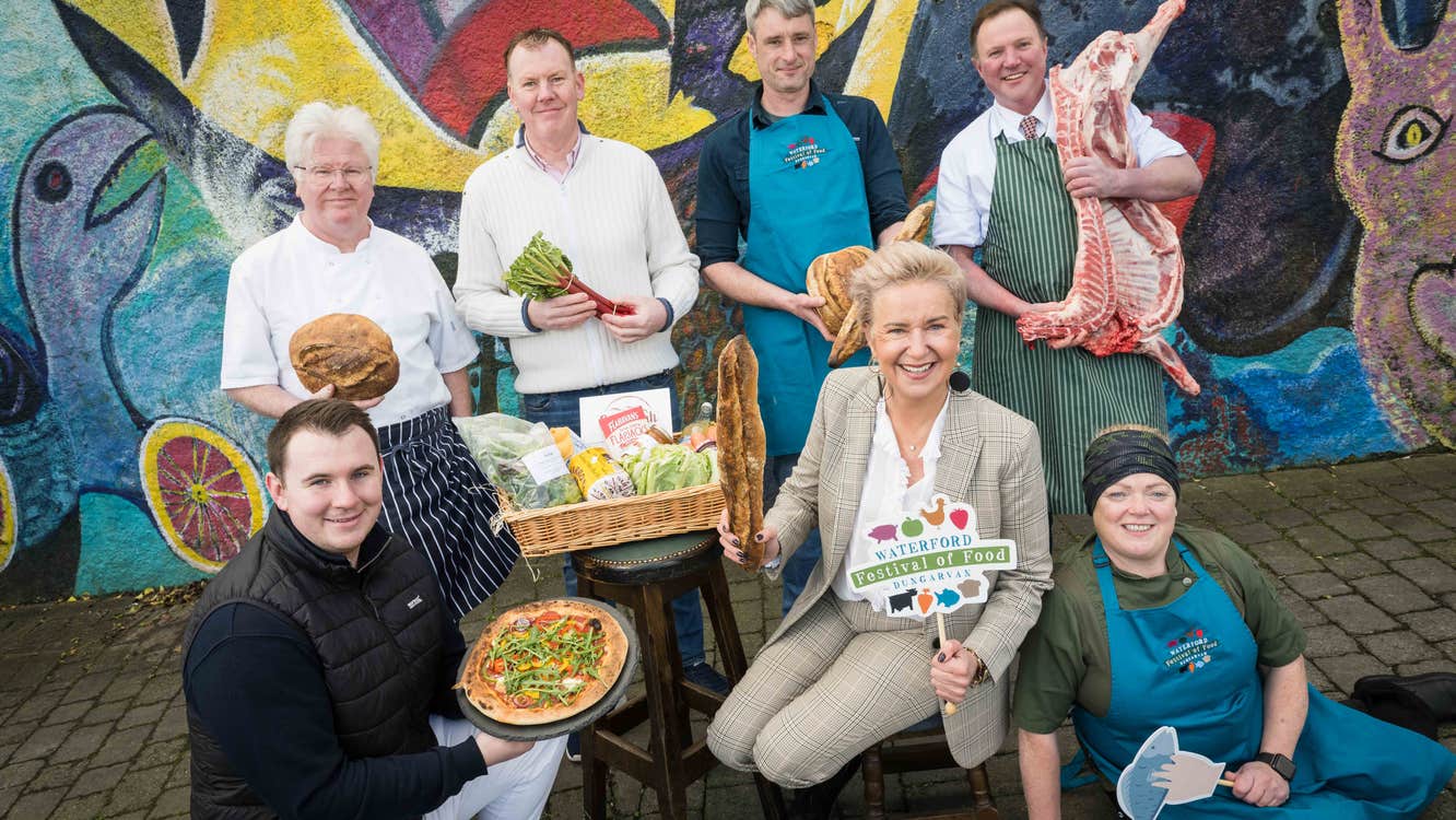 A group of smiling people each holding either food produce or small hashtag signs