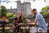 A couple sitting at a table with Kilkenny Castle in the background in County Kilkenny.