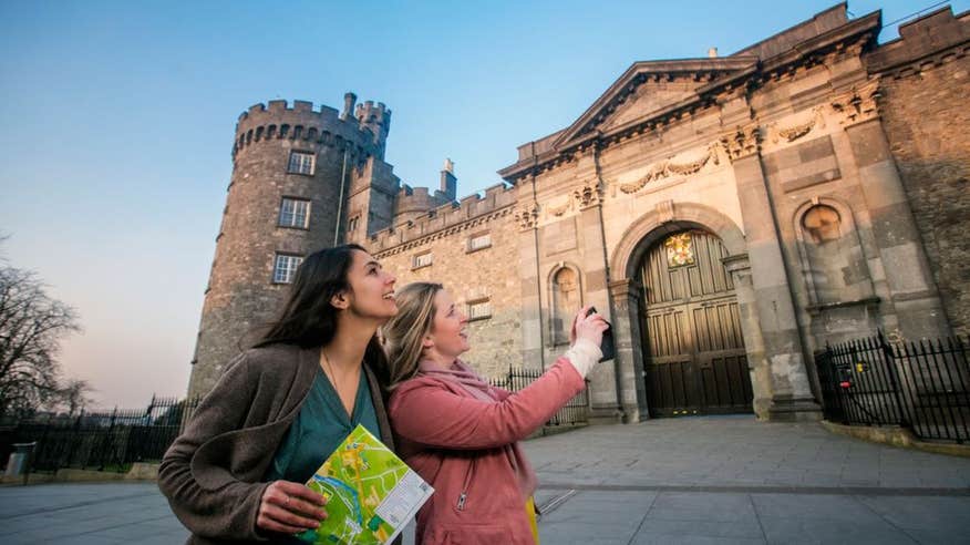 Two women taking pictures outside Kilkenny Castle, County Kilkenny