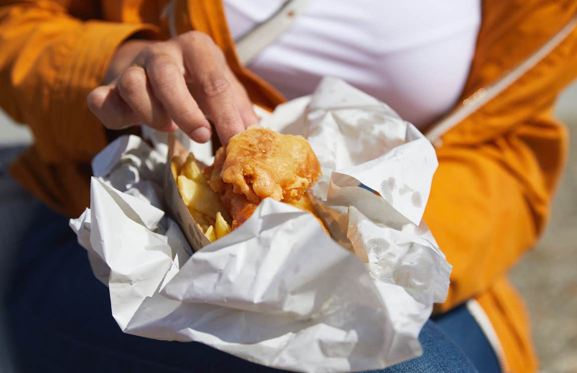 A person holding a portion of fish and chips