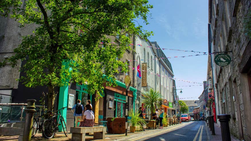 A street with brightly painted buildings, greenery and bunting in Galway City, Galway