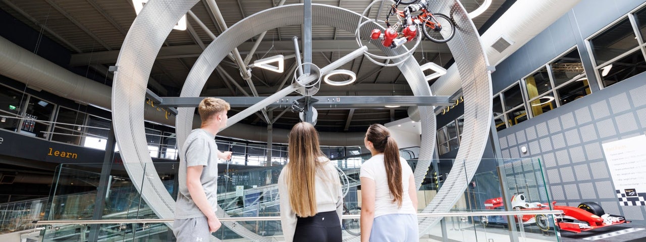 Children looking at metal rings with a bicycle and robot rider cycling along the circuit