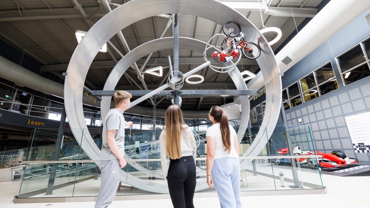 Children looking at metal rings with a bicycle and robot rider cycling along the circuit