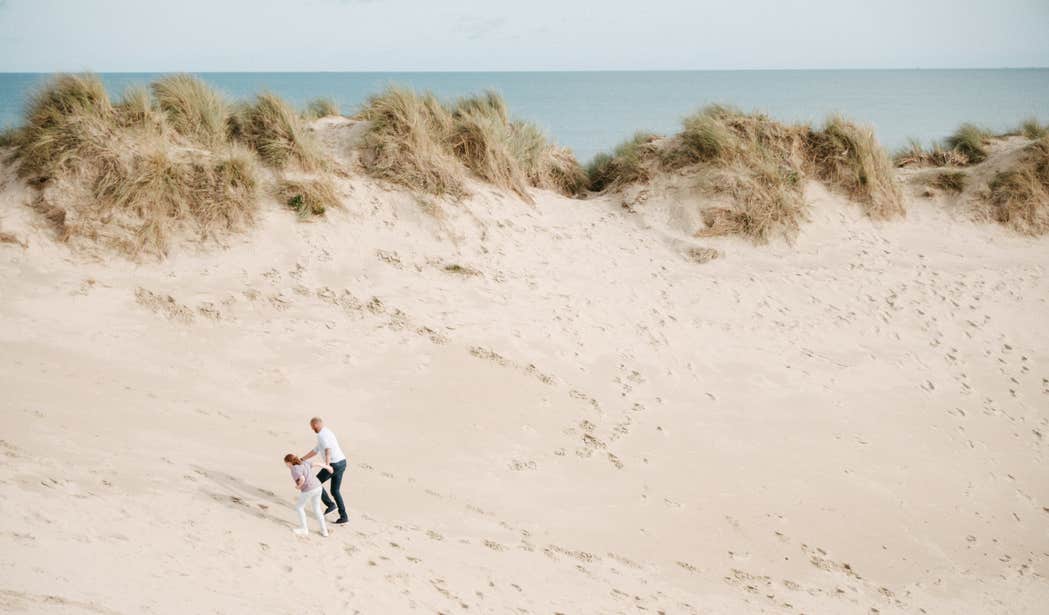 Two people walking up the sand dunes at Curracloe Beach in Wexford.