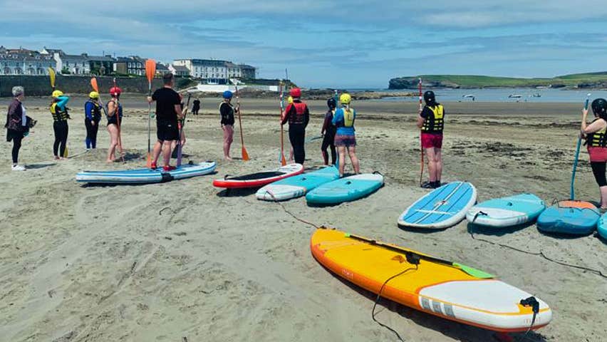 A group of paddleboarders practising on the sandy shore