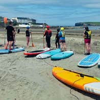 A group of paddleboarders practising on the sandy shore