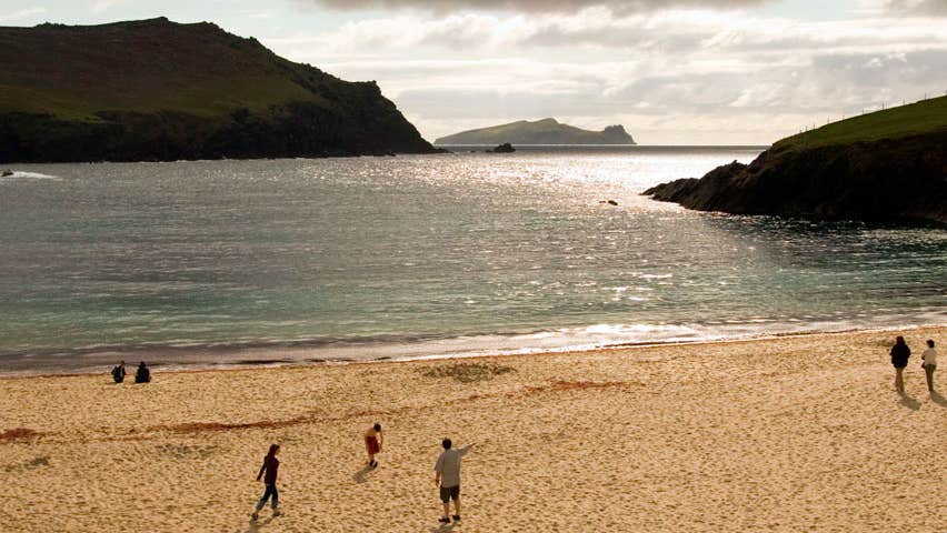 People walking in the distance on Clogher Beach in evening light