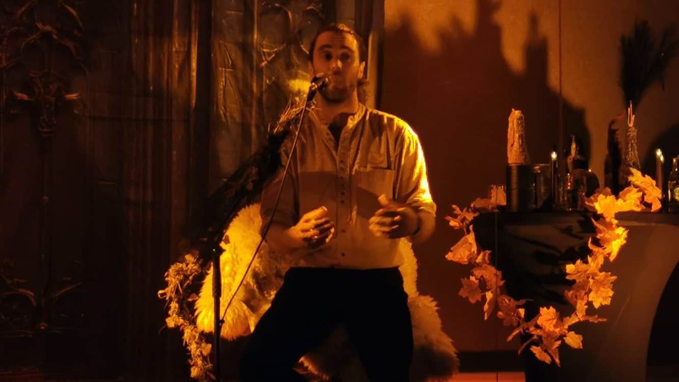 Man on stage singing/talking in candlelit lighting