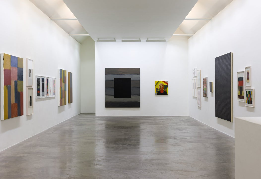 Art gallery with a grey floor and white walls displaying pictures