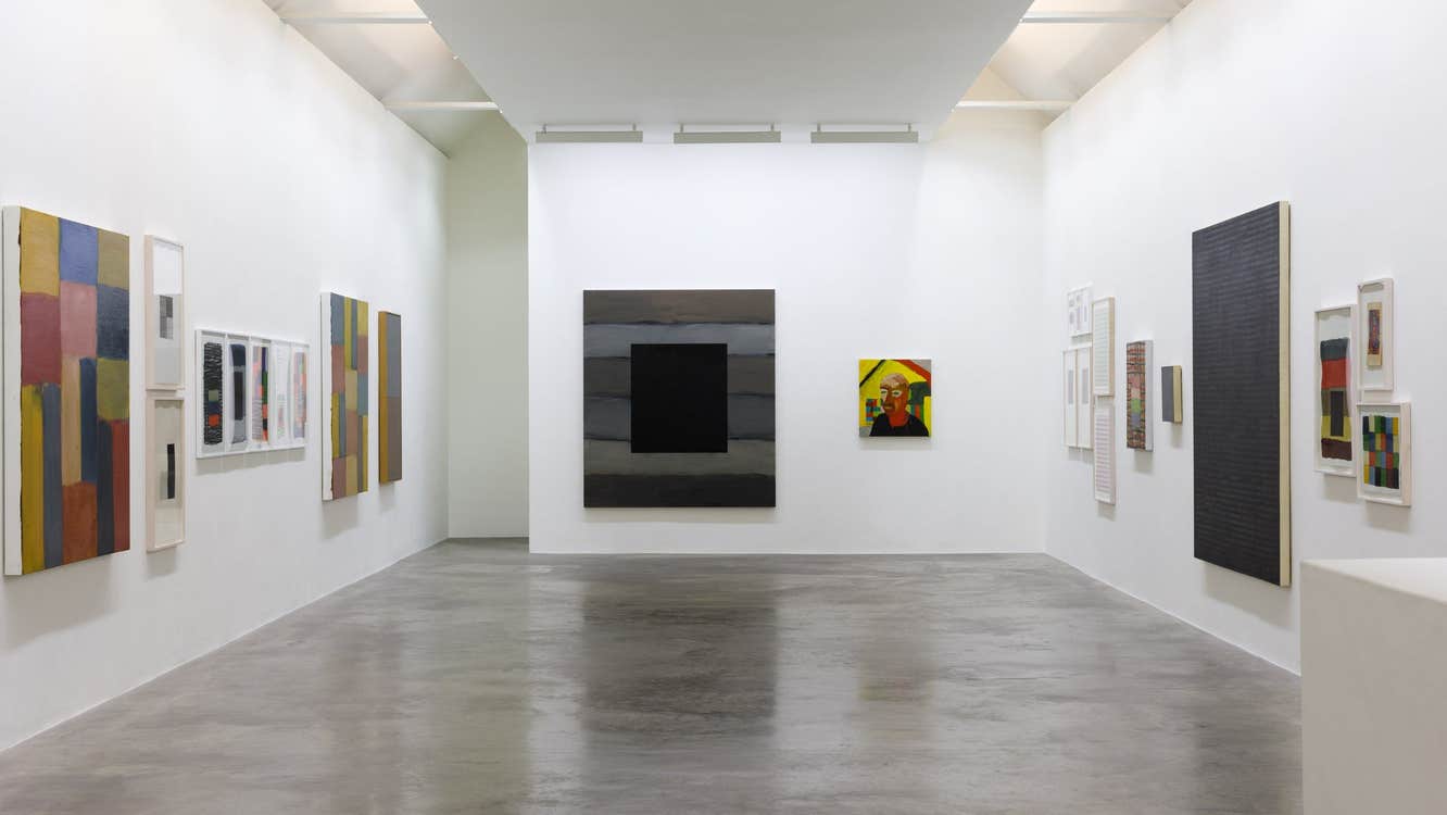 Art gallery with a grey floor and white walls displaying pictures