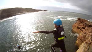 A person diving into the water from a cliff top with Wild Water Adventures in County Kerry.