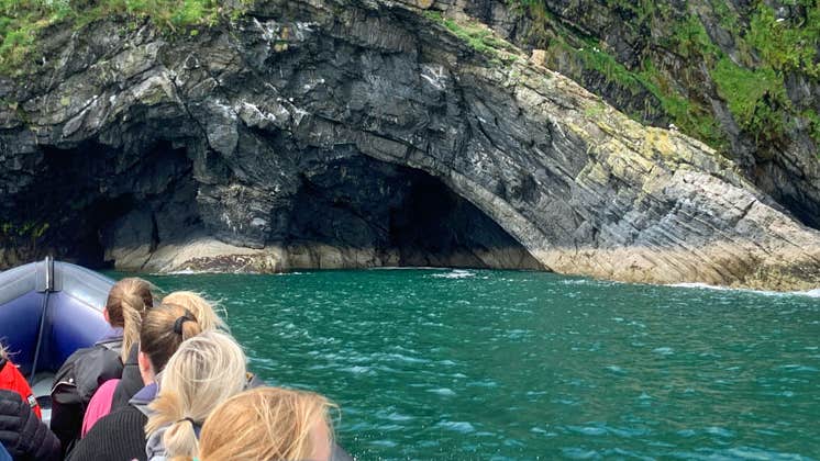 People on a boat on the sea going towards a sea cave