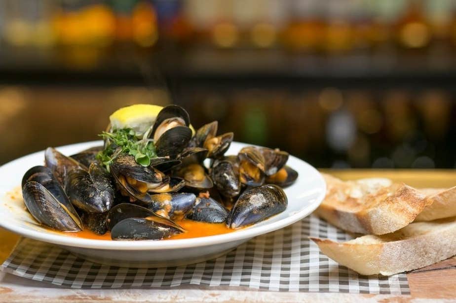 A bowl of mussels and slices of bread.