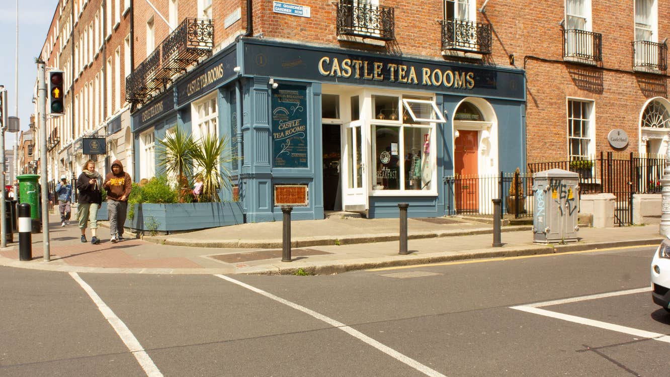 Street view of a blue coffee shop on a corner with people walking past