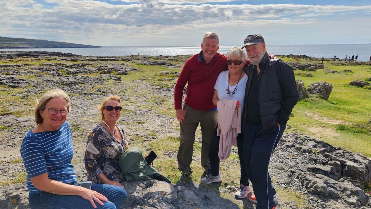 A group of people on tour with the ocean in the background