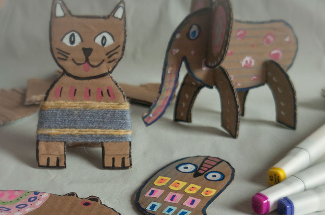 A cat and an elephant made out of brown card with simple drawn faces.