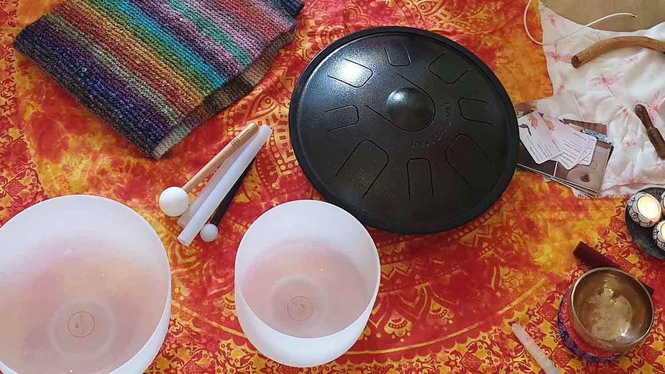 White, opaque glass bowls on a red and gold table cloth with small gongs and a stripy knitted piece of cloth.