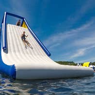 Someone sliding down an inflatable slide on a lake