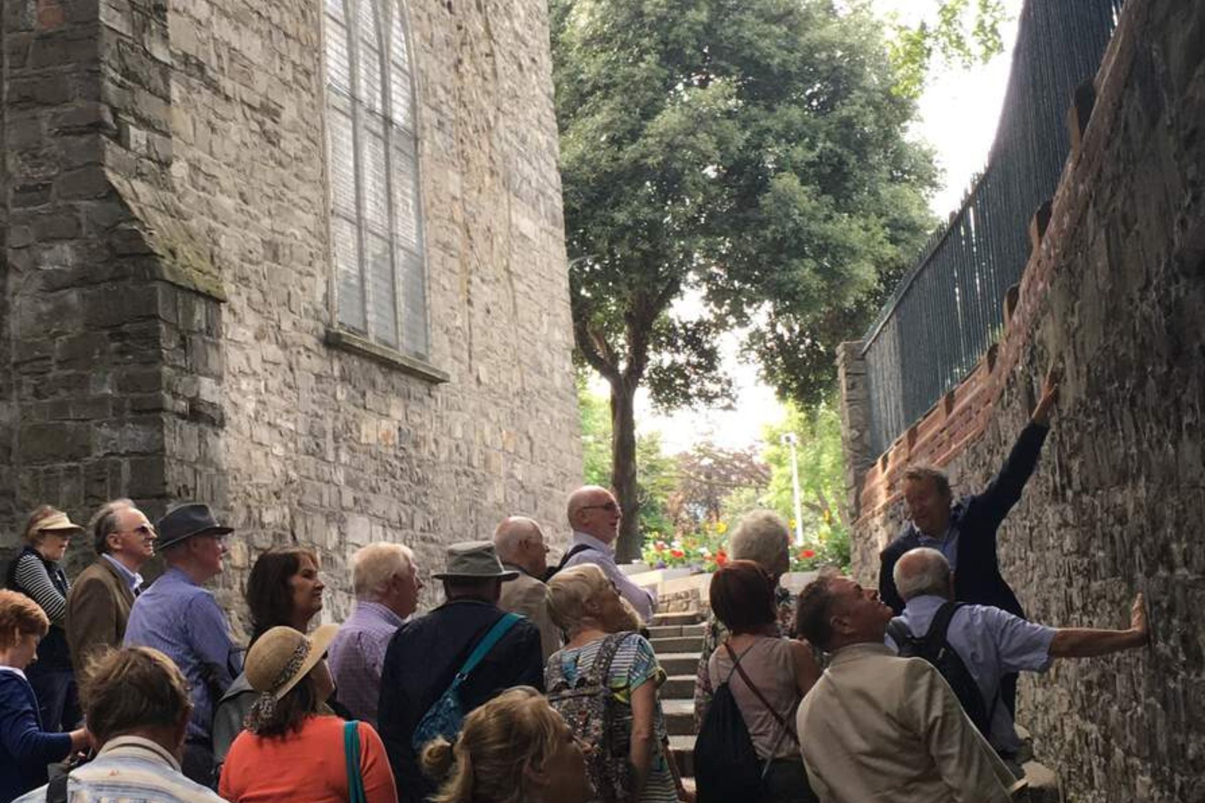 Dublin walking tour guide explaining to group the significance of a wall near stone steps.