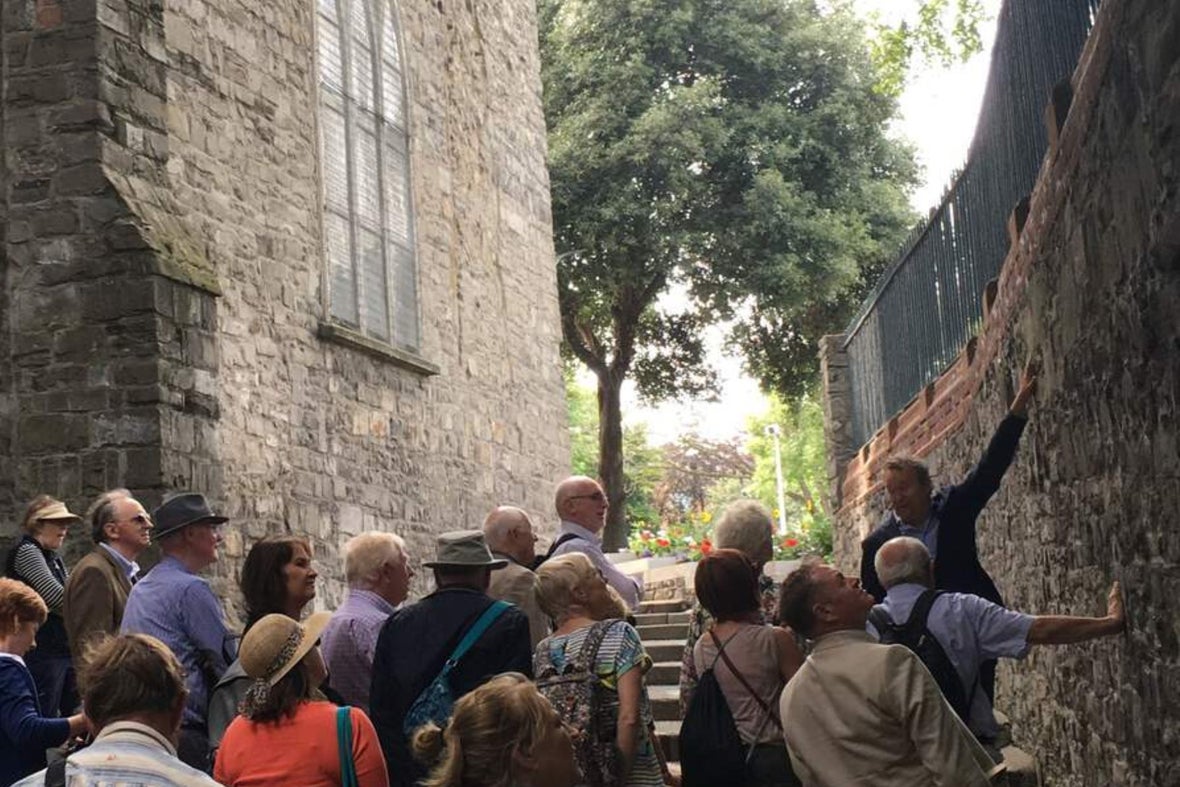 Dublin walking tour guide explaining to group the significance of a wall near stone steps.