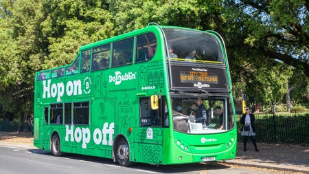 A double decker bus with a tour group on the streets of Dublin
