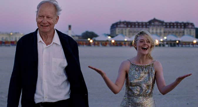 A joyous old man and young woman are on a beach.