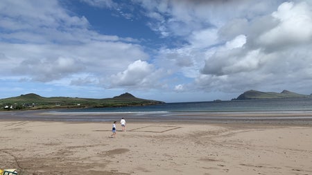 A couple walking on the sand at a beach along the Dingle Peninsula