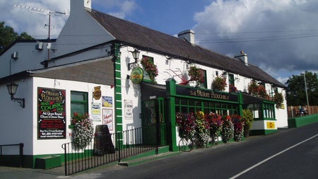 Exterior view of The Merry Ploughman Pub a white building with green trim and shopfront