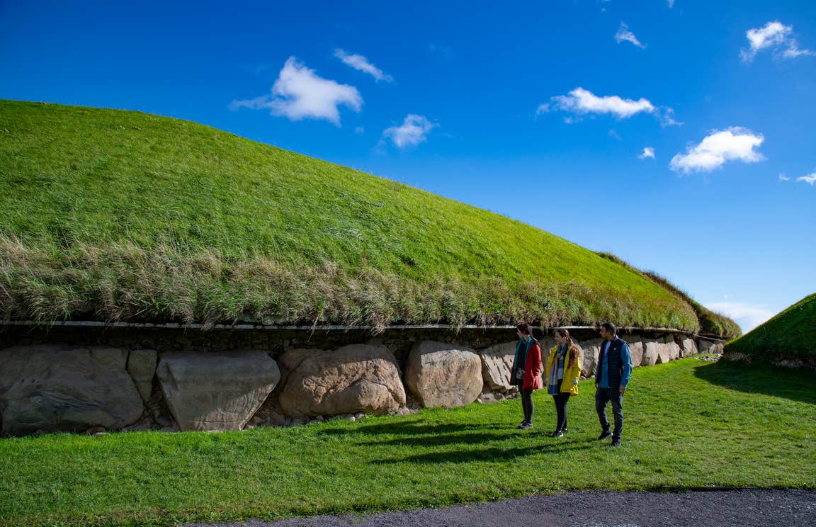 People walking beside the Knowth Neolithic tomb in Co Meath
